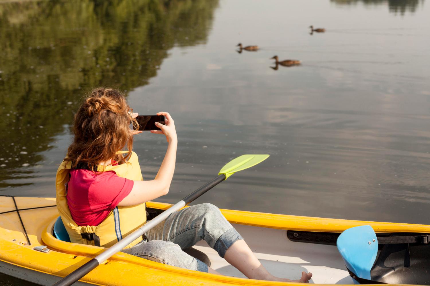 2 - A woman on a boat, snapping photos of swans